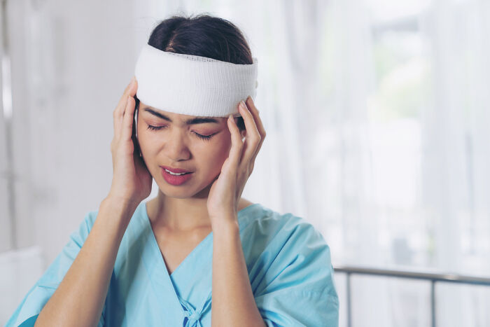 A young woman touching her bandaged head to show painful medical practices