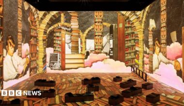 An interactive gallery featuring David Bowie. It depicts the musician lying down and reading a book. There are bookcases surrounding him.
