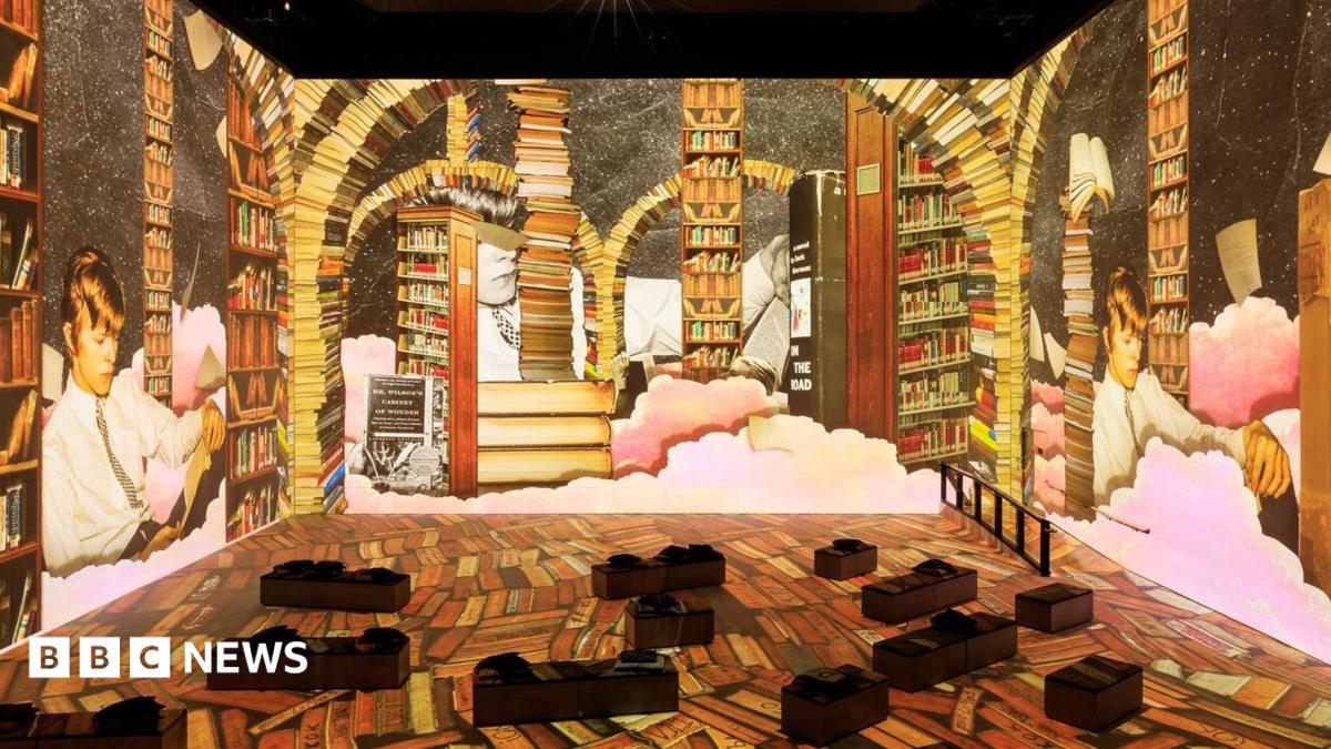 An interactive gallery featuring David Bowie. It depicts the musician lying down and reading a book. There are bookcases surrounding him.