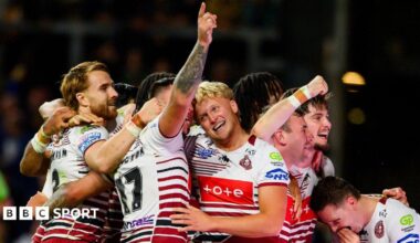 Wigan's Oliver Partington (17) has his right arm raised in celebration while being hugged by a number of team-mates after one of their seven tries against Leeds