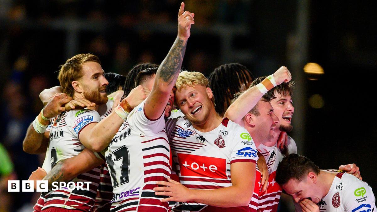 Wigan's Oliver Partington (17) has his right arm raised in celebration while being hugged by a number of team-mates after one of their seven tries against Leeds