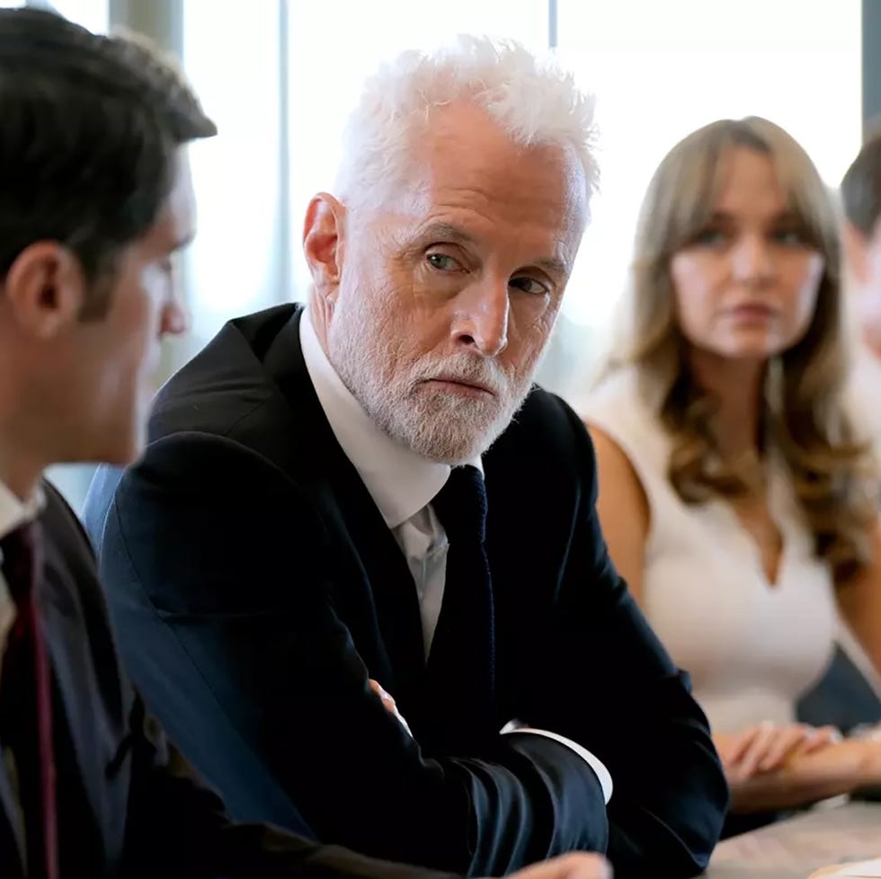 people in a boardroom meeting with serious expressions.