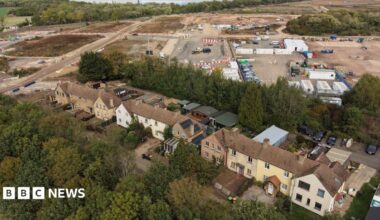 A row of houses with a construction sight in the background. There are buildings and patches of land being built on.