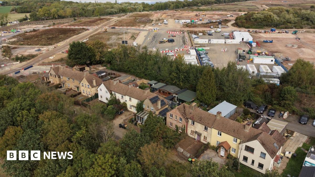 A row of houses with a construction sight in the background. There are buildings and patches of land being built on.
