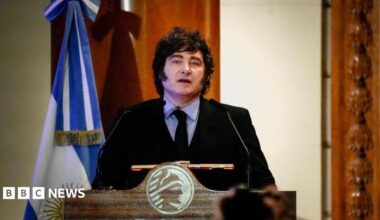 Argentine President speaks during a ceremony commemorating the 172nd anniversary of the Buenos Aires Stock Exchange in Buenos Aires, Argentina, July 16, 2026. He is wearing a dark suit with a black tie and a light blue shirt. He stands at a lectern and to his left there is an Argentine flag.