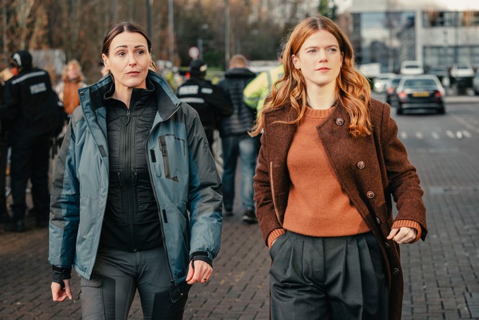 574847,TITLE:Vigil Suranne Jones as Amy Silva and Rose Leslie as DI Kirsten Longacre in Vigil, walking next to one another down a street.
