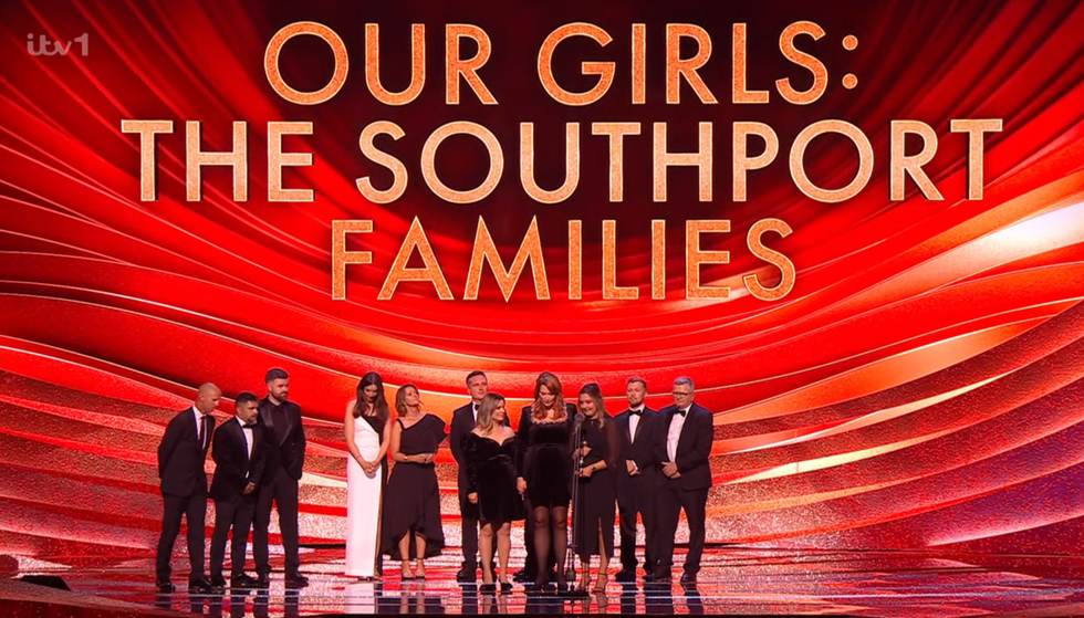 group on stage in front of red backdrop with "our girls: the southport families" text. group on stage in front of red backdrop with "our girls: the southport families" text.