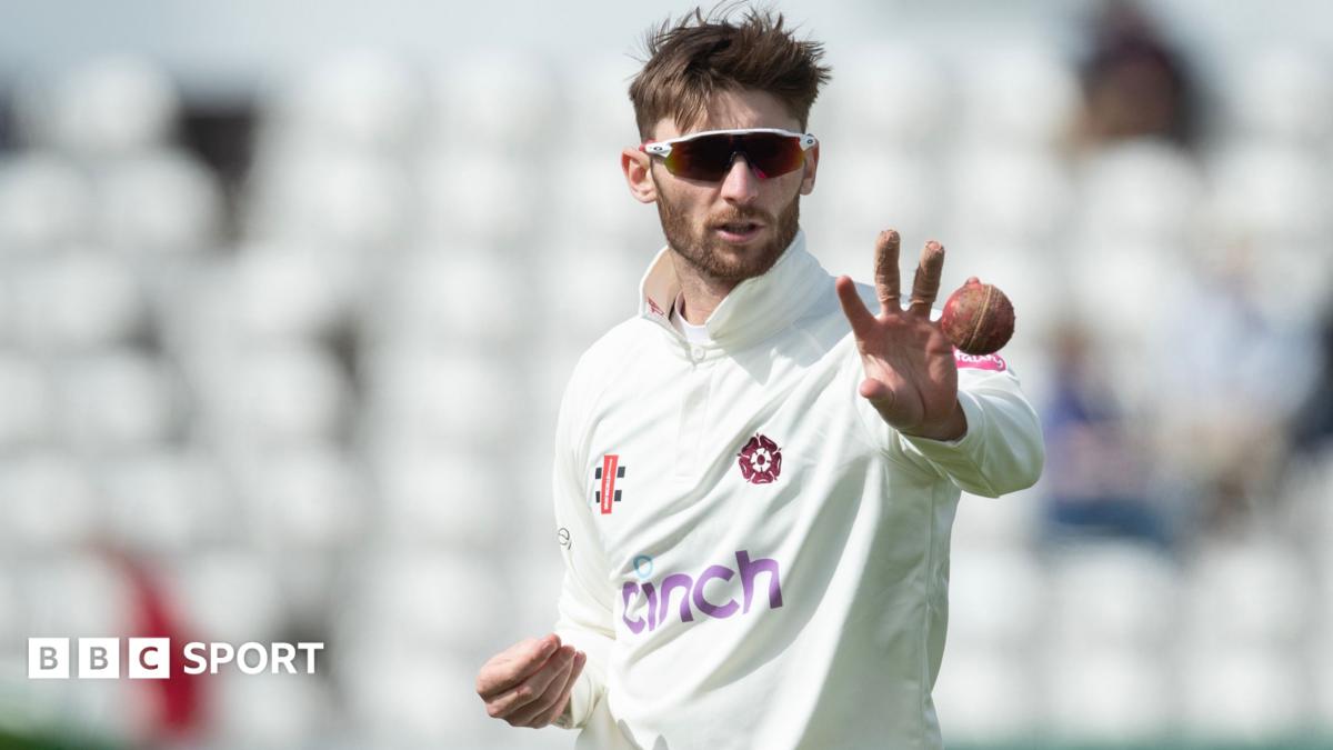 Rob Keogh, wearing sunglasses, catches a ball while preparing to bowl