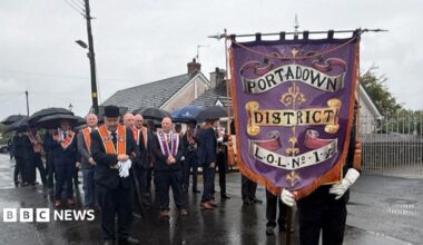 Orangemen gathering on a road, with sashes and a banner.