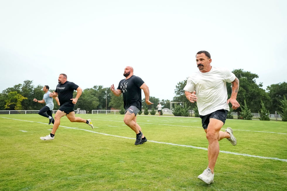 Four men running on a grassy field during a training session. Four men running on a grassy field during a training session.
