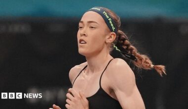 Joanna Wietrzyk wears a black sports bra and a dark headband with the words 'the feed' printed in green letters. Her hair is tied back into a plait and she is mid-run.