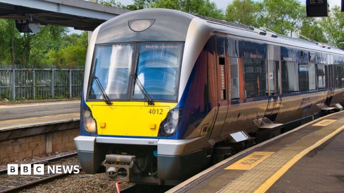 A train parked at a station. It is mostly blue and silver, and has a yellow box ohn the front.
