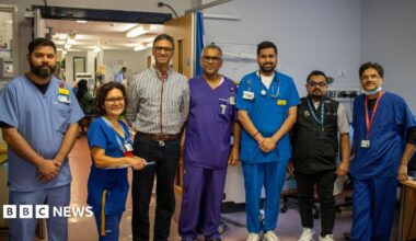 A group of doctors dressed in scrubs, shirts and a gilet.