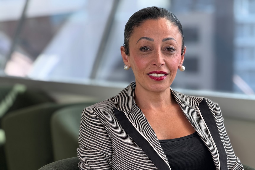 Shatha Hamade from Animals Australia smiles at the camera, while seated in a green tub chair.