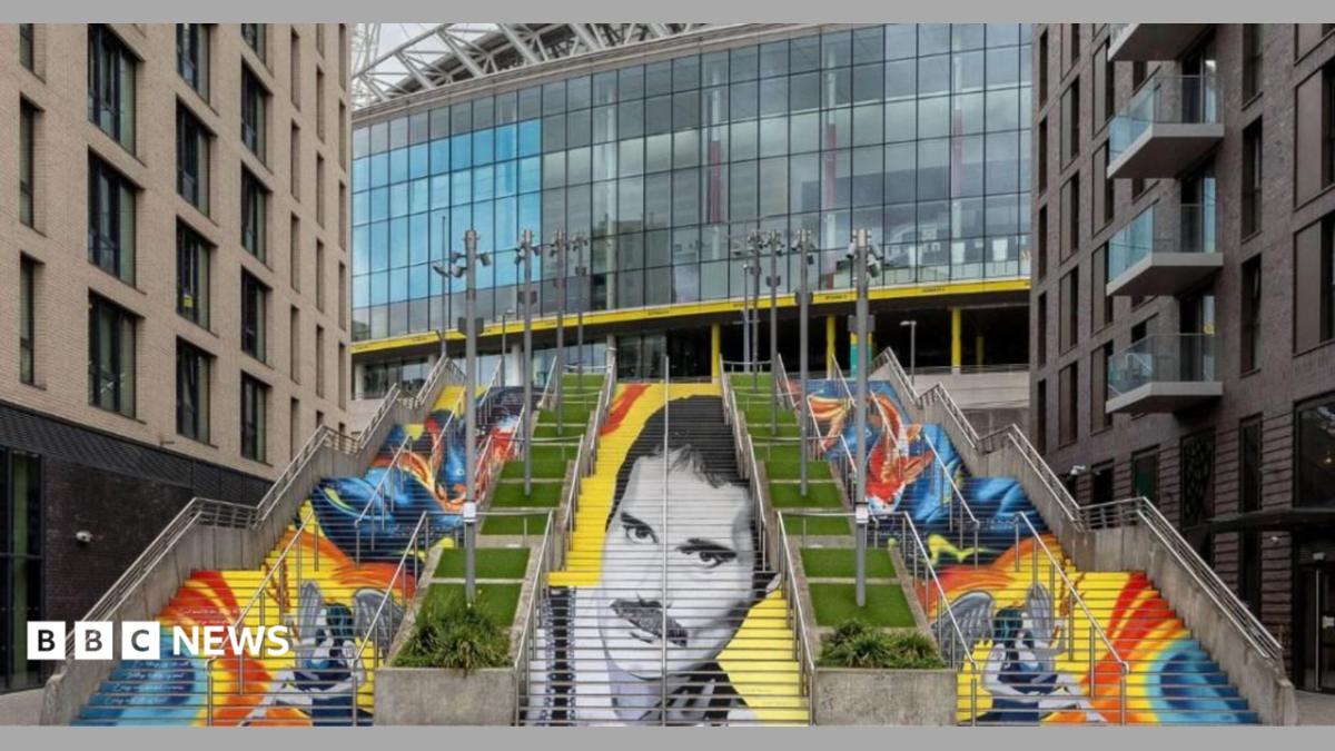 Painted steps seen from the front, with Freddie Mercury's face in black and white across the central flight and koi carp in orange and blue on the steps either side, Wembley Stadium behind