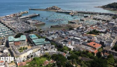 A drone picture of St Peter Port in Guernsey showing the islands busy capital with close buildings and the harbour in the background. Guernsey's castle cornet is in the background.