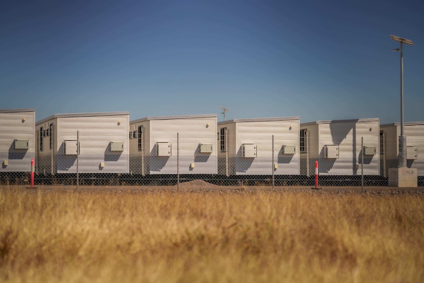 A row of demountable-style buildings behind a fence.