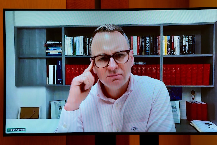 A man with his finger on his temple appears on a computer screen