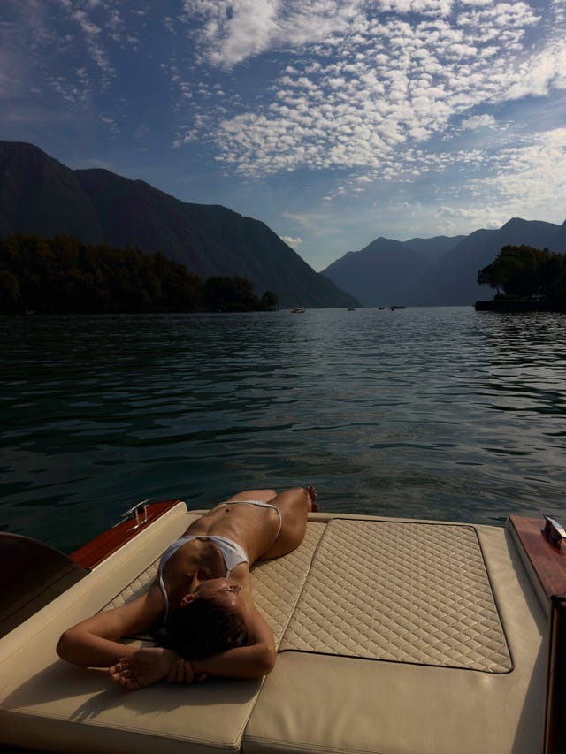 person sunbathing on a boat with mountain and lake view person sunbathing on a boat with mountain and lake view