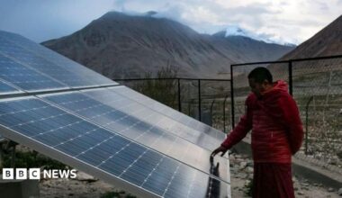 A monk touches solar panels at the Shachukul Monastery in the Ladakh region