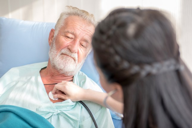 Nurse cares for elderly man lying in bed