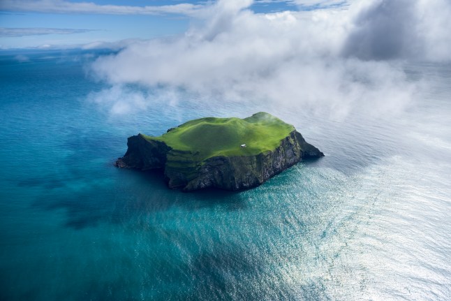 An green island surrounded by turquoise blue ocean