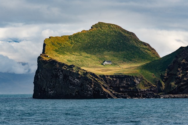 A house on a curve-shaped island surrounded by sea