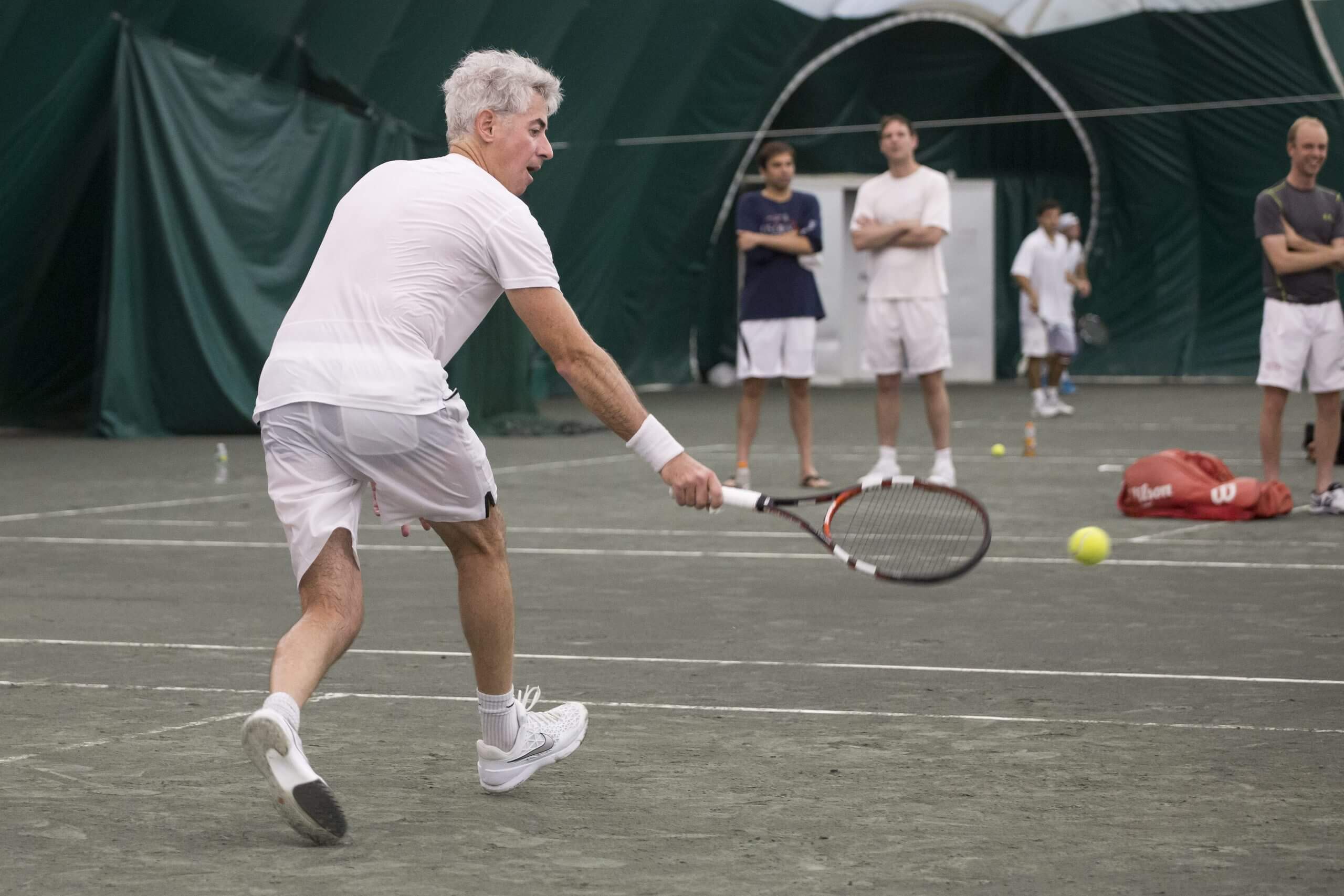 Bill Ackman on a tennis court in white clothing.