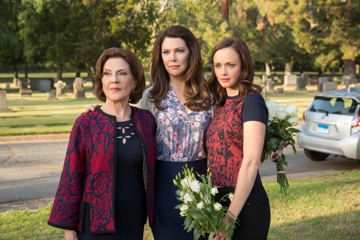 A collection of three generations of brunette women stood outside as group looking ahead.