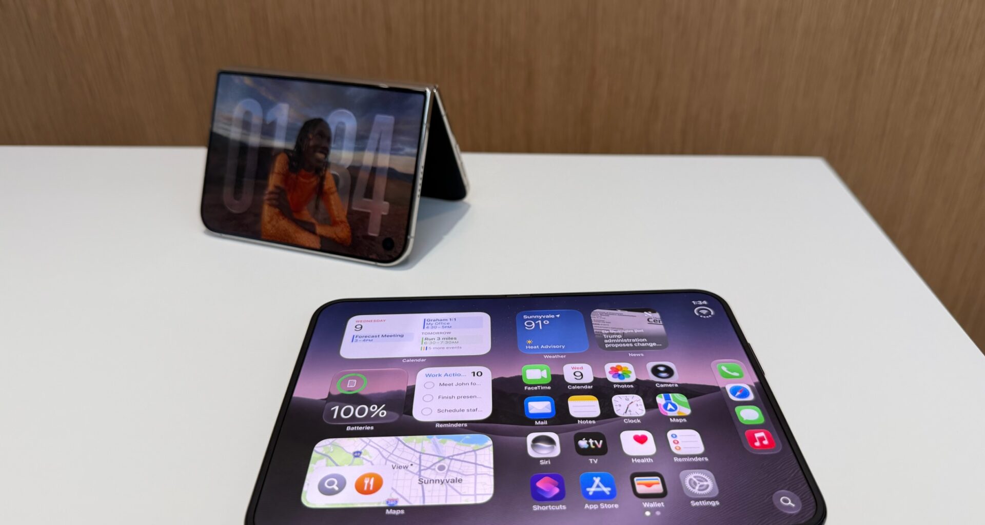 Two foldable phones on a table, one unfolded flat and one half-folded and upright like a tent.