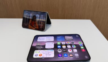 Two foldable phones on a table, one unfolded flat and one half-folded and upright like a tent.