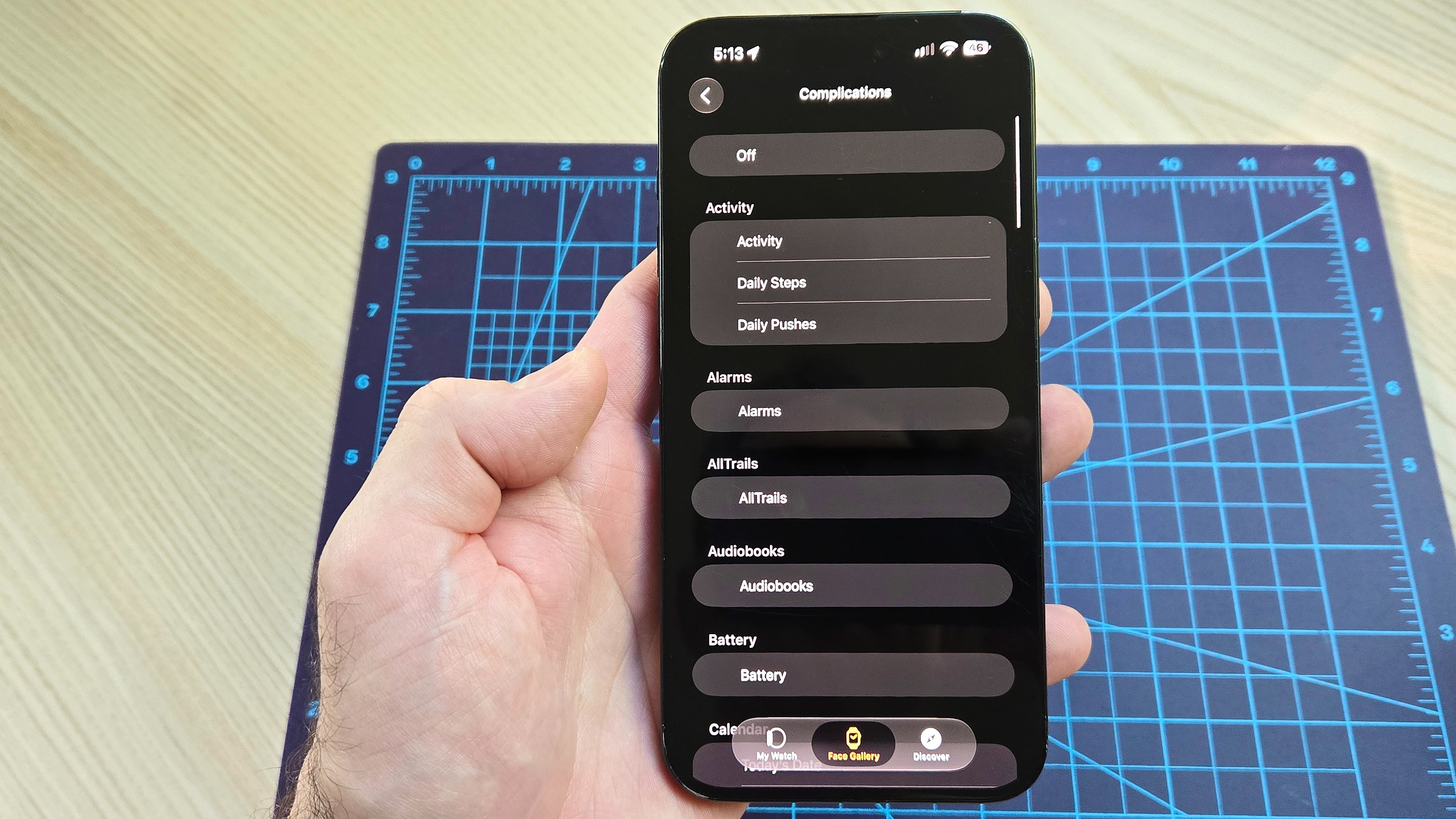 Close-up of an iPhone 16 Plus showing how to add the new step count widget to your Apple Watch's watch face