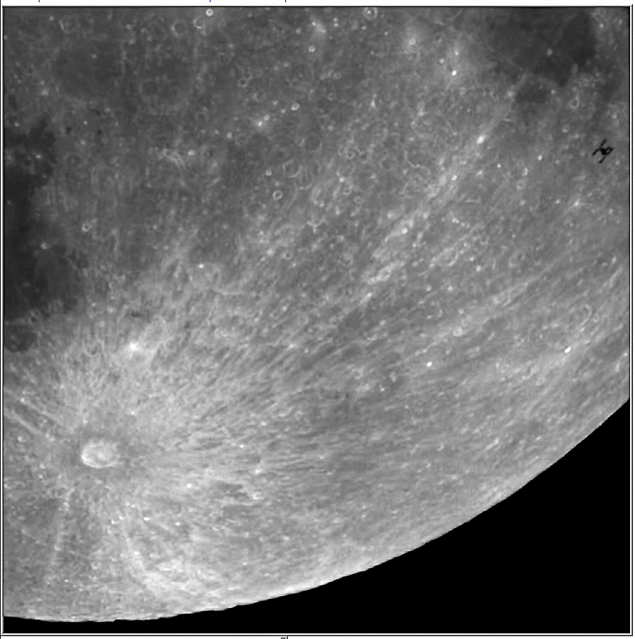 The black silhouette of a space station is shown moving across the face of the moon, travelling past a large crater to the lower left of the field of view.
