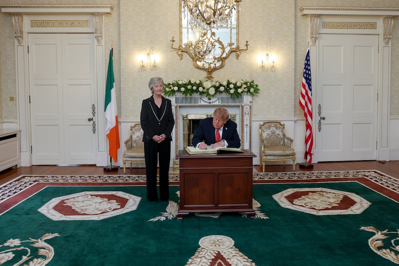 President Catherine Connolly watches as US President Donald Trump signs the visitors book at Aras an Uachtarain. Photograph: Tony Maxwell/Maxwells/PA Wire 