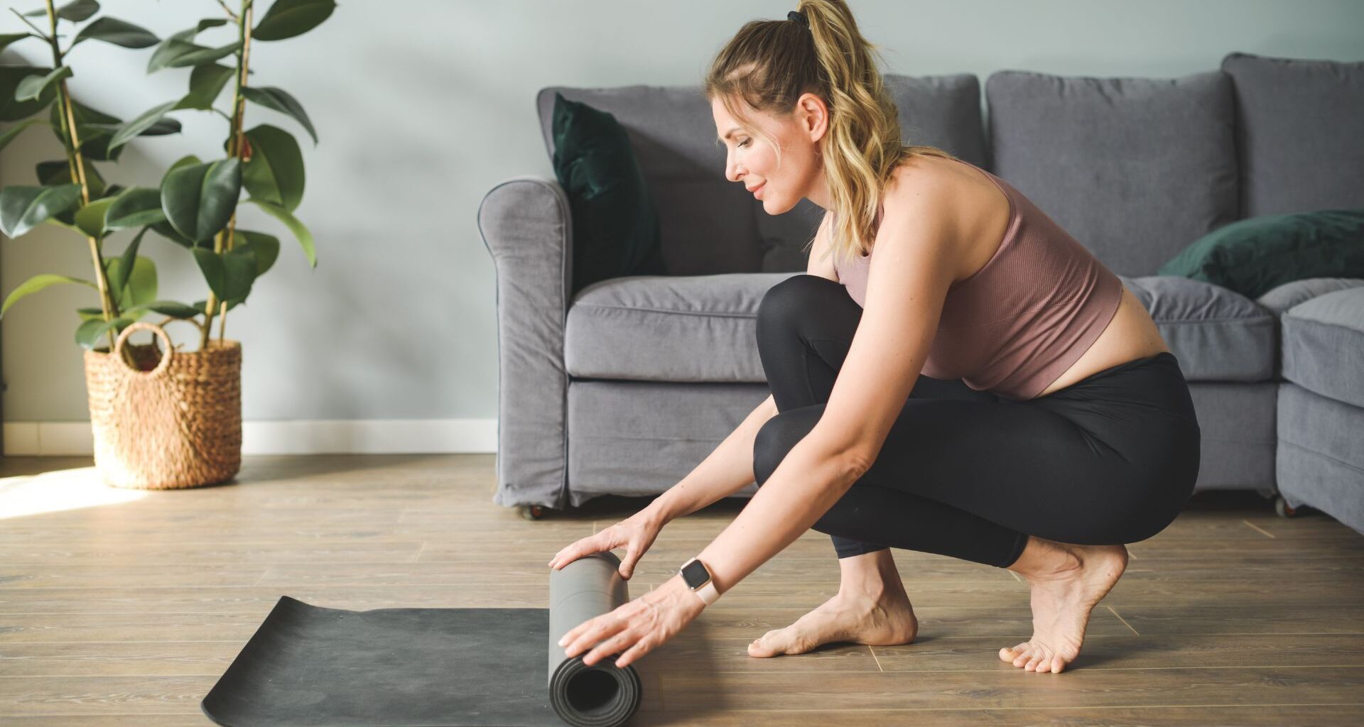 Woman rolling out yoga mat on the floor at home