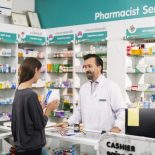 Pharmacist handing customer prescription in drug store