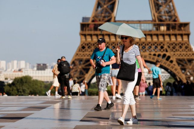A tourist holds an umbrella to protect themselves from the sun during a heatwave near the Eiffel Tower at the Trocadero square, in Paris, on June 30, 2025. French authorities put Paris on red alert for extreme heat and Spain and Portugal reported record temperatures as a heatwave gripped southern Europe and Britain on June 30, 2025, triggering health warnings and fuelling wildfires. (Photo by Ludovic MARIN / AFP) (Photo by LUDOVIC MARIN/AFP via Getty Images)