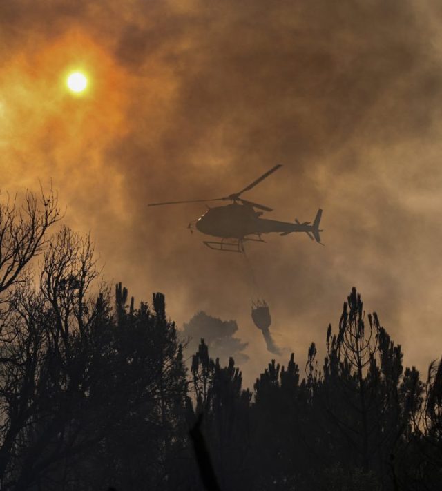 A firefighting helicopter drops water over a wildfire near the village of Larouco, in the province of Ourense, in northwestern Spain on August 13, 2025. Firefighters in Spain continue to battle fires across the country, where one volunteer has died while trying to extinguish a blaze, according to local authorities. Another man has died of burns near the capital city, Madrid. Across Europe, thousands have been forced from their homes by wildfires fuelled by an enduring heatwave. (Photo by MIGUEL RIOPA / AFP) (Photo by MIGUEL RIOPA/AFP via Getty Images) *** BESTPIX ***