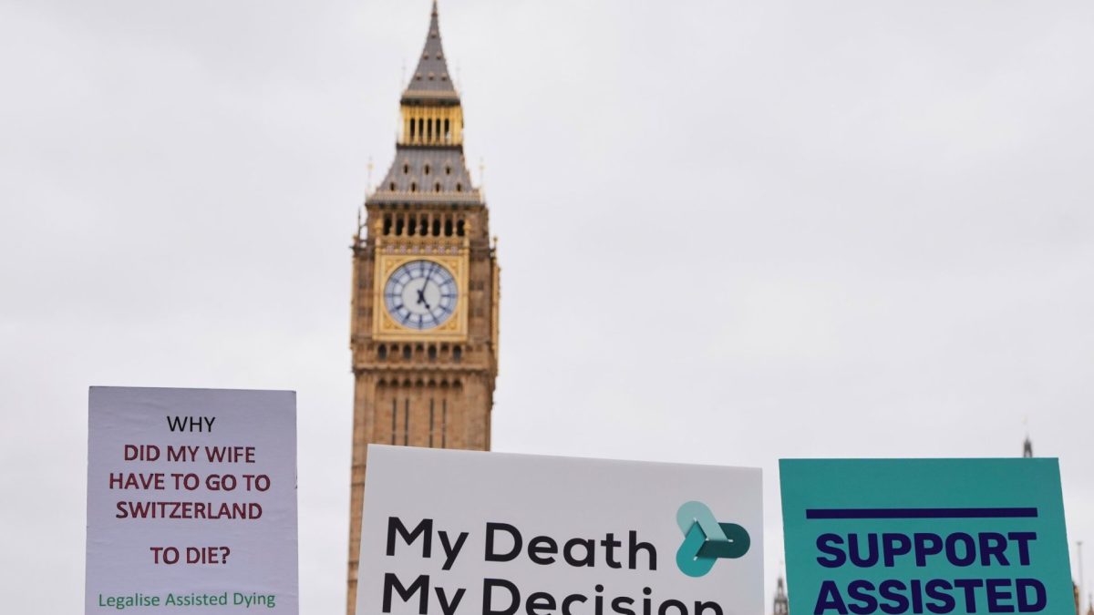FILE - Banners are held by pro-assisted dying campaigners as they gather outside Parliament in Westminster in London, May 15, 2025. (AP Photo/Kirsty Wigglesworth, File)