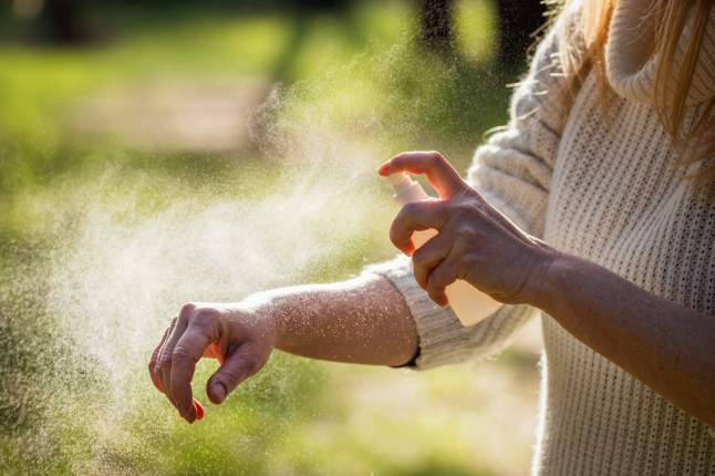 Insect repellent. Woman tourist applying mosquito repellent on hand during hike in nature. Skin protection against tick and mosquito bite