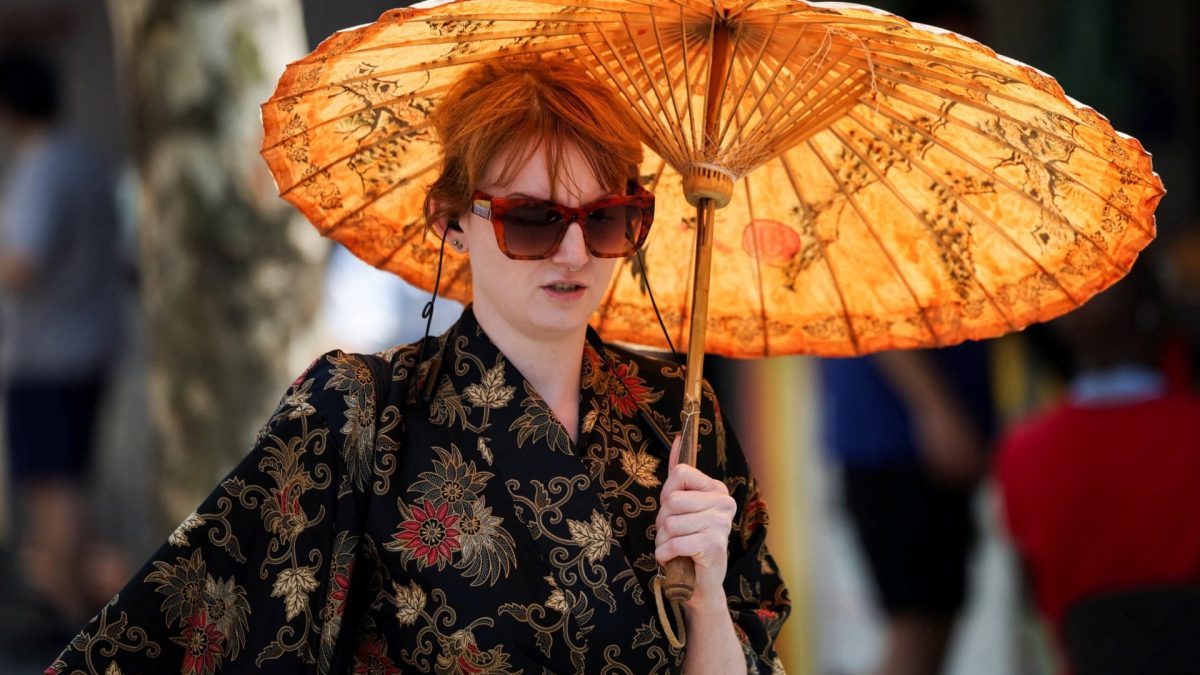 A woman shelters herself beneath an umbrella amid a heatwave, as Britain experiences record temperatures that disrupts schools and transport networks, in Manchester, Britain June 26, 2026. REUTERS/Temilade Adelaja