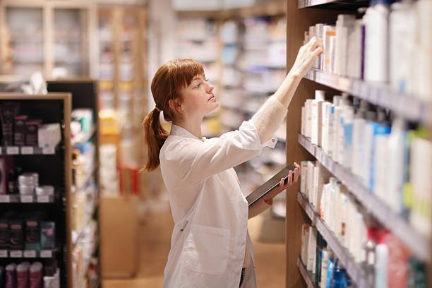 A pharmacist taking inventory of medications on the shelves of a pharmacy.