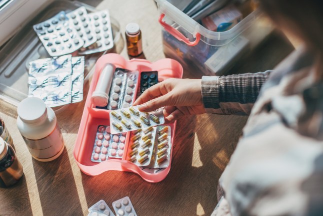 A woman places items inside a domestic first aid kit.