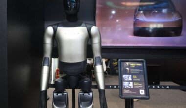Tesla's Optimus Gen-3 humanoid robot at an exhibition in Hangzhou, Zhejiang Province, China on September 23, 2026. The robot is standing in front of a screen displaying a car.