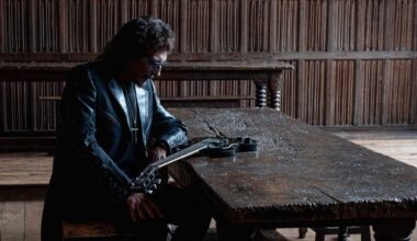 Tony Iommi sitting at a wooden table with a Gibson SG