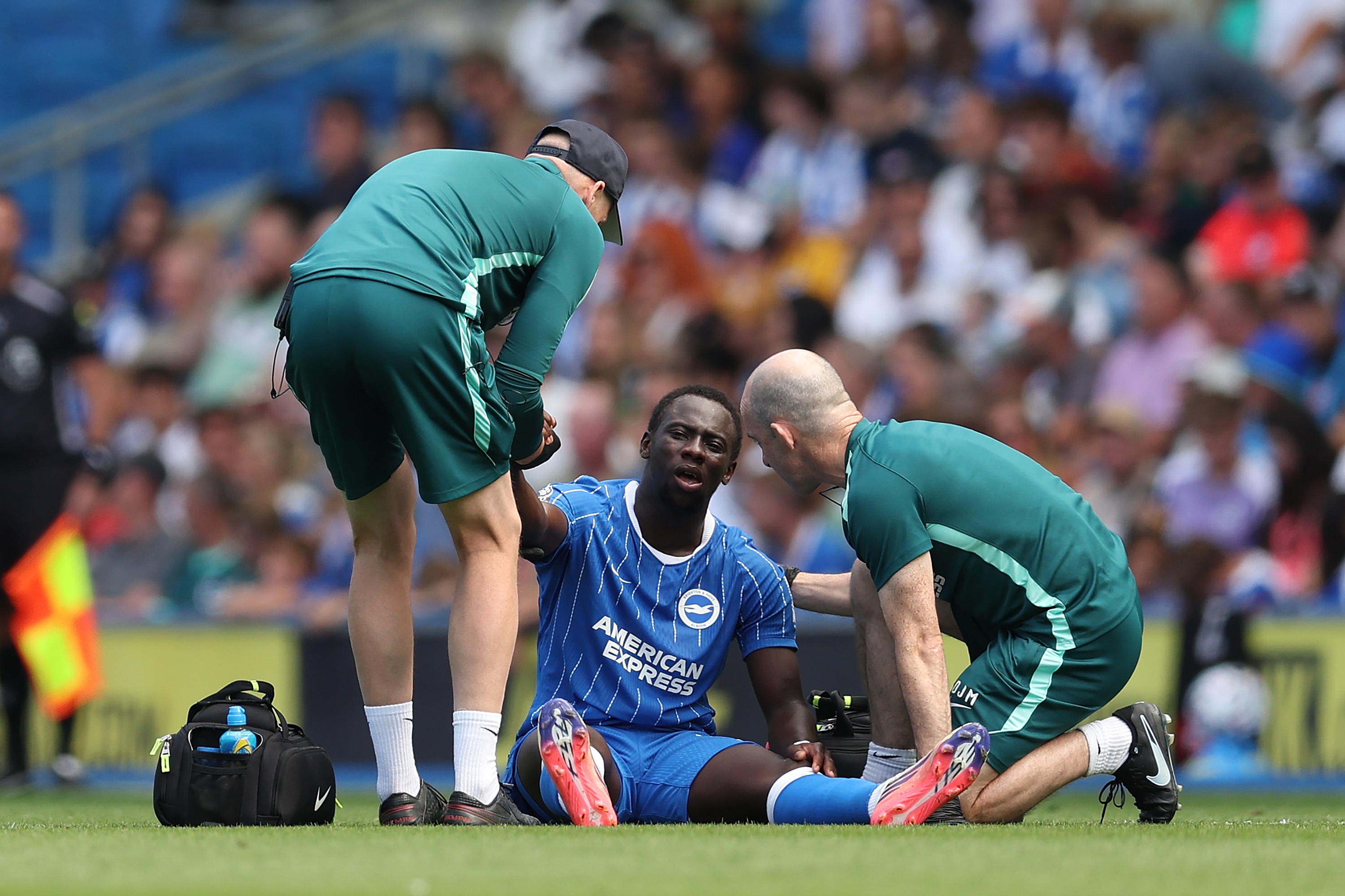 Liverpool transfer target Yankuba Minteh sits on the floor and is tended to by Brighton physios.