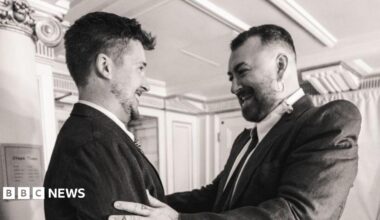 Bradley Jago and Sam Smith smiling as they meet. They have their hands on each other's arms.
