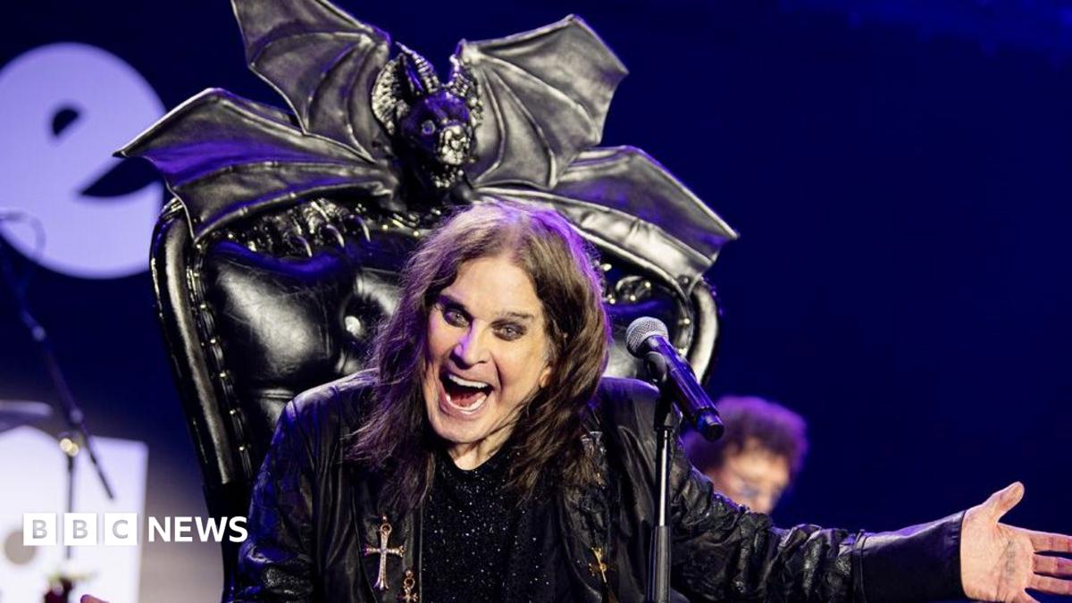 Ozzy Osbourne on stage with his arms outstretched and smiling