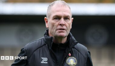 Russ Wilcox wearing a black jacket with a Gainsborough Trinity badge on the chest