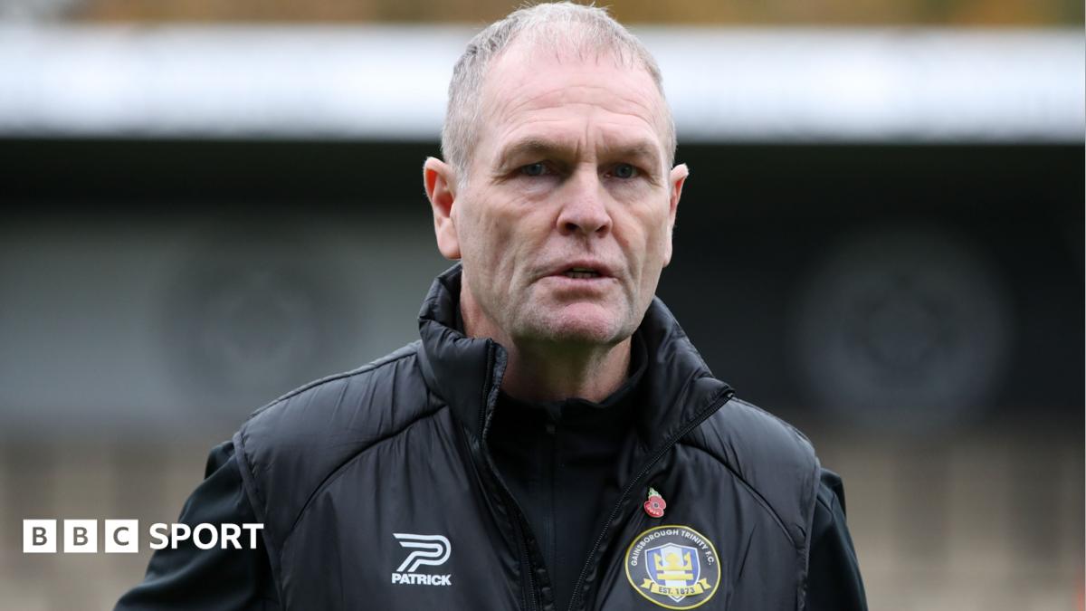 Russ Wilcox wearing a black jacket with a Gainsborough Trinity badge on the chest